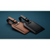 A brown and a black recycled leather luggage tag with a buckle strap, featuring a simple design and branding.