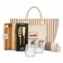 A tote bag with stripes, a wooden cheese board, a two-piece cheese set, two textured glasses, and a striped blanket.