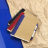 A set of spiral-bound notebooks in red, black, and blue, accompanied by a blue ballpoint pen on crumpled paper.