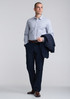 A slim fit long sleeve shirt in light blue, paired with navy trousers, featuring a jacket draped over one arm.