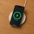 A wireless charger with a natural stone surface and a black smartphone displaying a charging indicator.