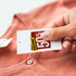 A hand holding a discount tag against a coral-coloured cardigan. The tag displays a percentage discount. A hand holding a discount tag against a coral-coloured cardigan. The tag displays a percentage discount.