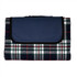 A picnic rug featuring a tartan pattern in navy blue, white, and red, with a solid navy flap and a branding logo.