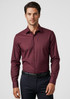 A maroon long sleeve button-up shirt with a fitted design and a logo. Styled with dark trousers.