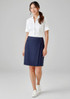 A woman wearing a navy skort and a white shirt, standing in a neutral background. The skort features a logo.