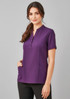 A women's tunic in a rich purple colour with short sleeves and pockets, featuring a button-up placket and a logo.