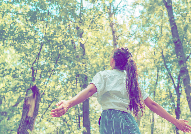 A girl looking at the sky in a wood