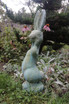 Silly Bunny statue in copper rust finish among the garden