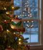 Blown glass ball ornament with holly leaf design on tree