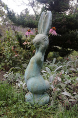 Silly Bunny statue in copper rust finish among the garden