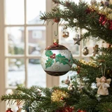 Blown glass ball ornament with holly leaf design on Christmas tree