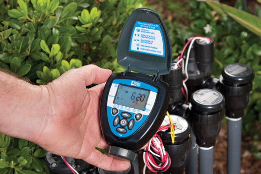 Hand holding DIG Battery Operated Controller in outdoor garden setting MPN: 7X0A-000