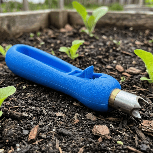 Netafim 7mm Punch resting on dark soil in a garden bed next to young plants MPN: PPPUNCH-7