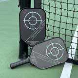 Engage Pursuit MAXX MX 6.0 Friction Carbon Pickleball Paddles on court leaning a against a net.