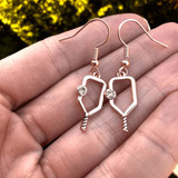 View of the Rose Gold Born to Rally Pickleball Dangle Earrings in models hand.