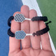 View of the Blue and Black Born to Rally Pickleball Stainless Steel Carbon Fiber Bracelet next to each other in models hand.