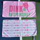View of both sides of the Born to Rally Dink Responsibly Double-Sided Microfiber Towel in the color Pink displayed on pickleball court.