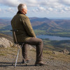 Person using the Trio Maxi Folding Seat Stick as a tripod seat while enjoying a countryside view.