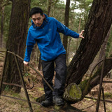 Man wearing Highlander Stow and Go waterproof jacket with peaked hood during wet weather woodland walk