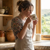 Women in kitchen drinking from walking boots china mug