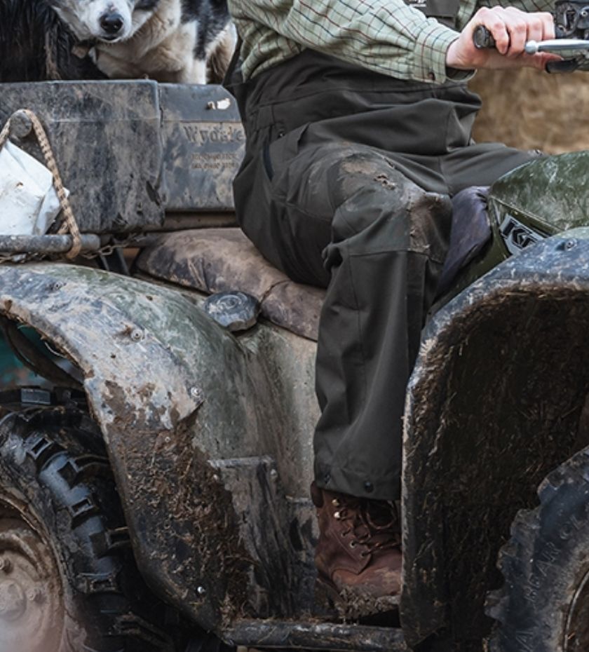 Farmer trousers. Farmer on quad bike wearing waterproof trousers