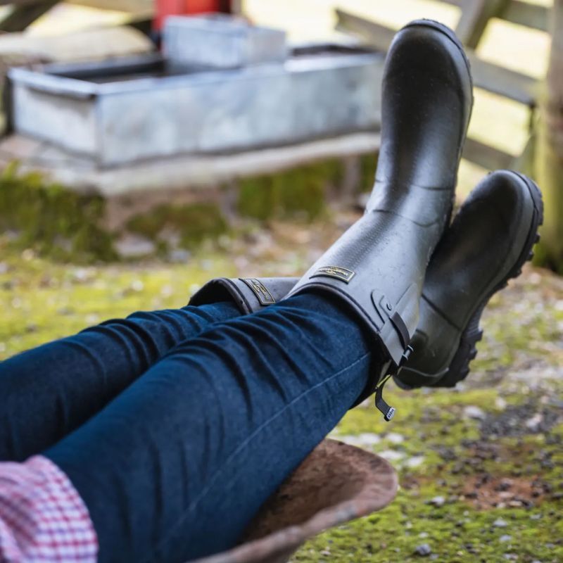 Gardener wearing wellies outdoors with a wheelbarrow
