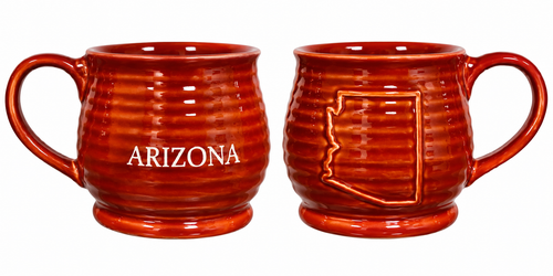 Two views of a glossy reddish-orange ceramic Arizona souvenir mug on a white background. The front view displays the word “ARIZONA” in white lettering, while the back view features a raised outline of the state of Arizona. The mug has a ribbed, textured body, rounded pedestal-style base, and curved handle.
