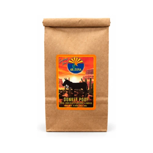 Kraft paper bag of Donkey Poop milk chocolate-covered almonds featuring a colorful Arizona souvenir label with a donkey silhouette, desert sunset, red rock formations, and saguaro cacti. Net weight 4 oz (113.30 g).