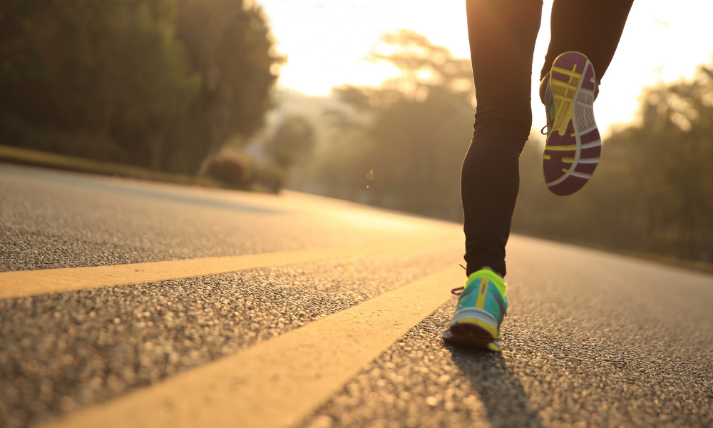 Performance running shoes on asphalt road at sunrise