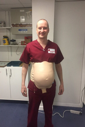 Midwifery student practicing medical checks on a dummy belly prop