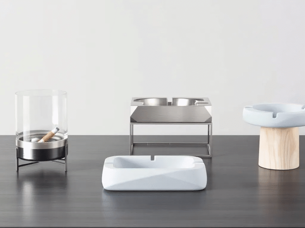 Various types of ashtrays including glass, metal, and silicone displayed together.