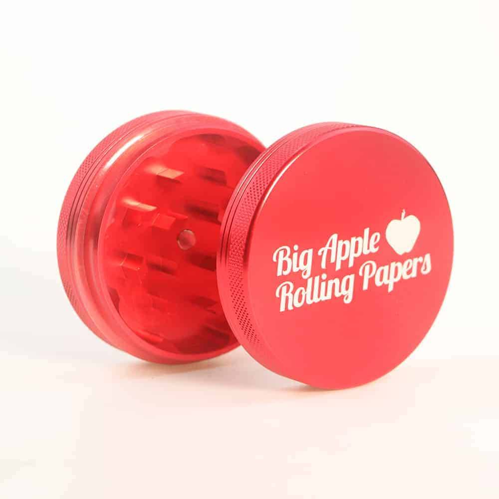 A laser engraved 2-piece aluminum grinder next to rolling papers.