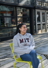 Classic sport grey MIT hooded sweatshirt featuring bold varsity lettering and the official MIT Crest. Soft, durable with a front pocket and drawstring hood. Timeless collegiate style.