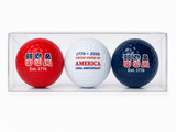 Three commemorative USA 250th Anniversary golf balls in a clear display gift box featuring red, white, and navy patriotic designs with "USA Est. 1776" and "1776–2026 United States of America 250th Anniversary" graphics.