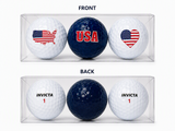 Three patriotic golf balls in a clear display gift box featuring a USA map with the American flag, a navy USA golf ball, and an American flag heart design.