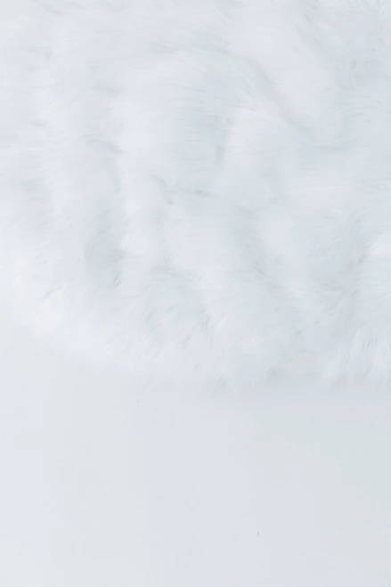 A circle shape long pile fur fabric in color white.