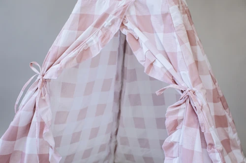 The Brandy Play Tent is a dark blush pink gingham/buffalo plaid play tent with vertical ruffles along the front panels.