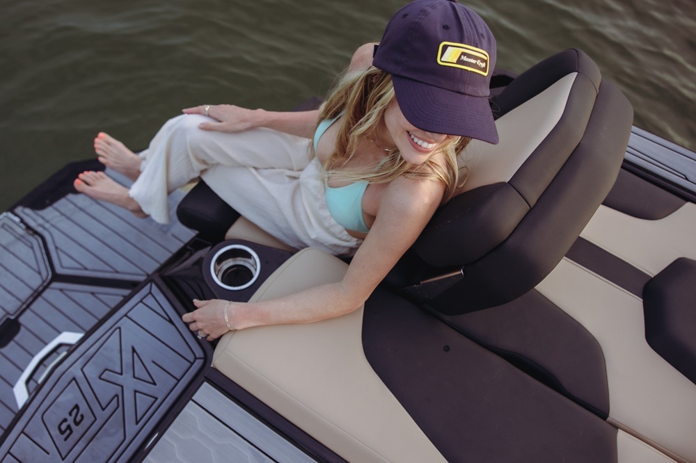 Woman relaxing on MasterCraft boat with gray SeaDek flooring and X-series logo