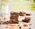Twelve Better For You brownies cut into squares on parchment paper, seen from above, with a knife and a small pitcher of plant-based milk.