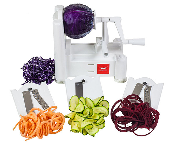 Paderno tri-blade spiral vegetable slicer holding a red cabbage, with its three blade plates in front and piles of spiralized carrot, zucchini, and beet.