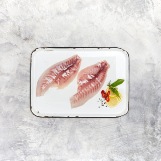 Red snapper fillet on tray with garnish and lemon.