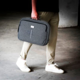 A grey laptop bag with a handle is being carried by a person in casual attire.