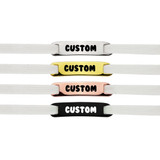 Four shoelace charms in white, yellow, pink, and black, each with a customisable design and featuring a logo.