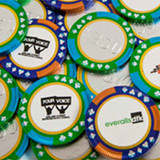 A collection of chocolate poker chips in green, blue, and orange, featuring various branded stickers on the sides.