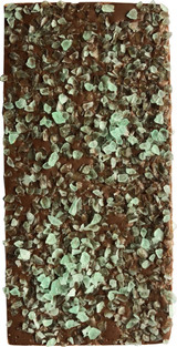 A milk chocolate bar topped with green peppermint crystals, featuring a textured surface and a glossy finish.