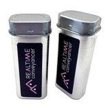 Two silver tin containers with a hinged lid and a black sticker featuring a logo. They are designed for mints.