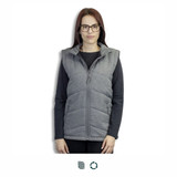 A woman wearing a grey puffer vest with a zip front, featuring a hood and pockets. The vest has a logo.