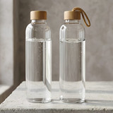 A glass drink bottle with a wooden lid and a rope loop, containing clear water, featuring a sleek design.