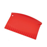 A red ice scraper with a curved edge and teeth along one side. It features a hole for hanging.