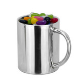 A silver coffee mug filled with colourful jelly beans and featuring a handle.